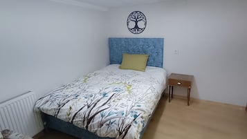 Quarto com cama, mesa de cabeceira, decoração na parede e radiador.