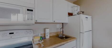 A compact kitchen with a microwave, a sink, and a refrigerator.