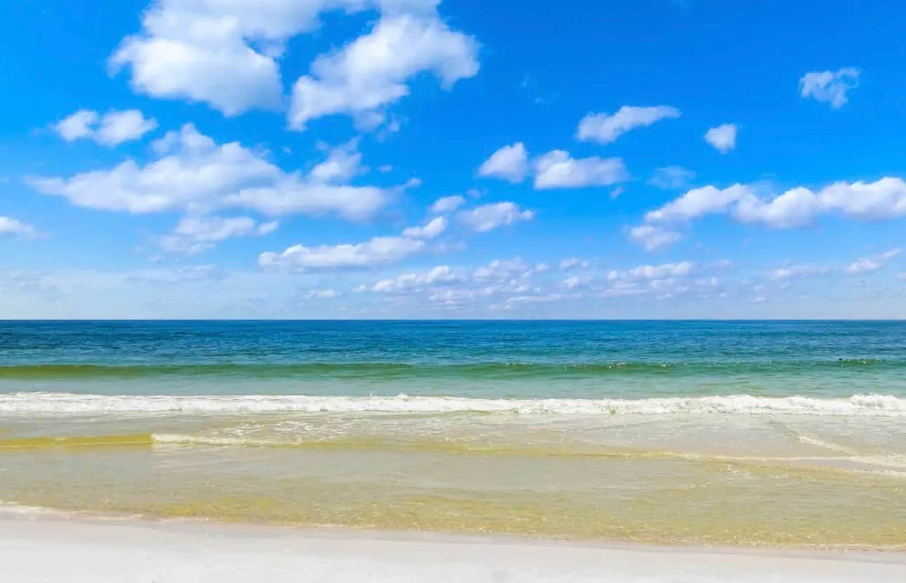 Ein Strand mit blauem Himmel und ruhiger Wellenbewegung.