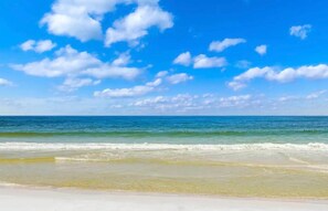 Ein Strand mit blauem Himmel und ruhiger Wellenbewegung.