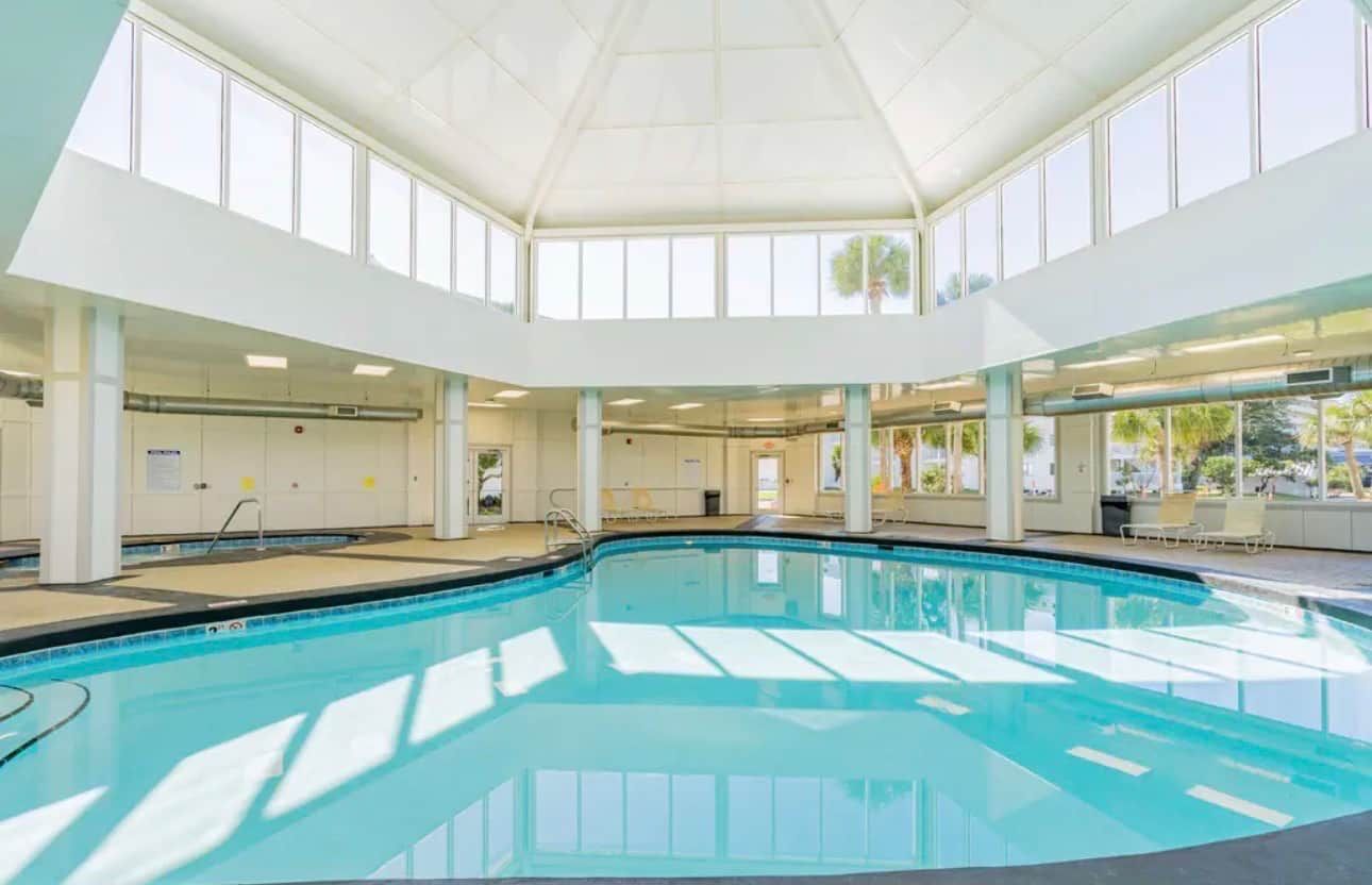 Ein Hallenbad mit hoher Decke und großen Fenstern.