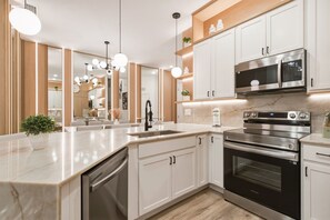 Een moderne keuken met witte kasten, roestvrijstalen apparatuur en een marmeren aanrecht.