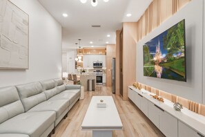 Een moderne woonkamer met een bank, een salontafel en een aan de muur bevestigde televisie.