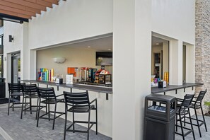 An outdoor bar area with black bar stools, a counter with various beverages, and a stone wall. - 5BR Villa Near Disney, Universal & SeaWorld! (Orlando)