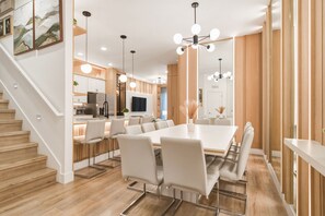 A modern kitchen with a dining area, wooden flooring, and a staircase. - 5BR Villa Near Disney, Universal & SeaWorld! (Orlando)