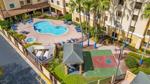 A hotel courtyard with a swimming pool, lounge chairs, and a basketball court. - Harry Potter Apartment | Near Universal (Orlando)