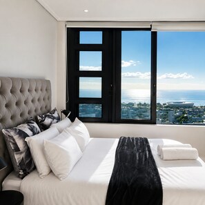 A hotel room with a large bed, a view of the sea, and a cityscape. - 16 on bree (Cape Town)