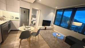 A modern apartment with a dining area, kitchen, living space, and a large window with a city view. - 16 on bree (Cape Town)