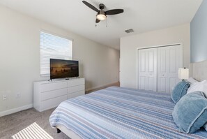 A bedroom with a bed, a television on a dresser, a ceiling fan, and a door. - 5-Bedroom Family House with Pool and Themed Rooms (Kissimmee)