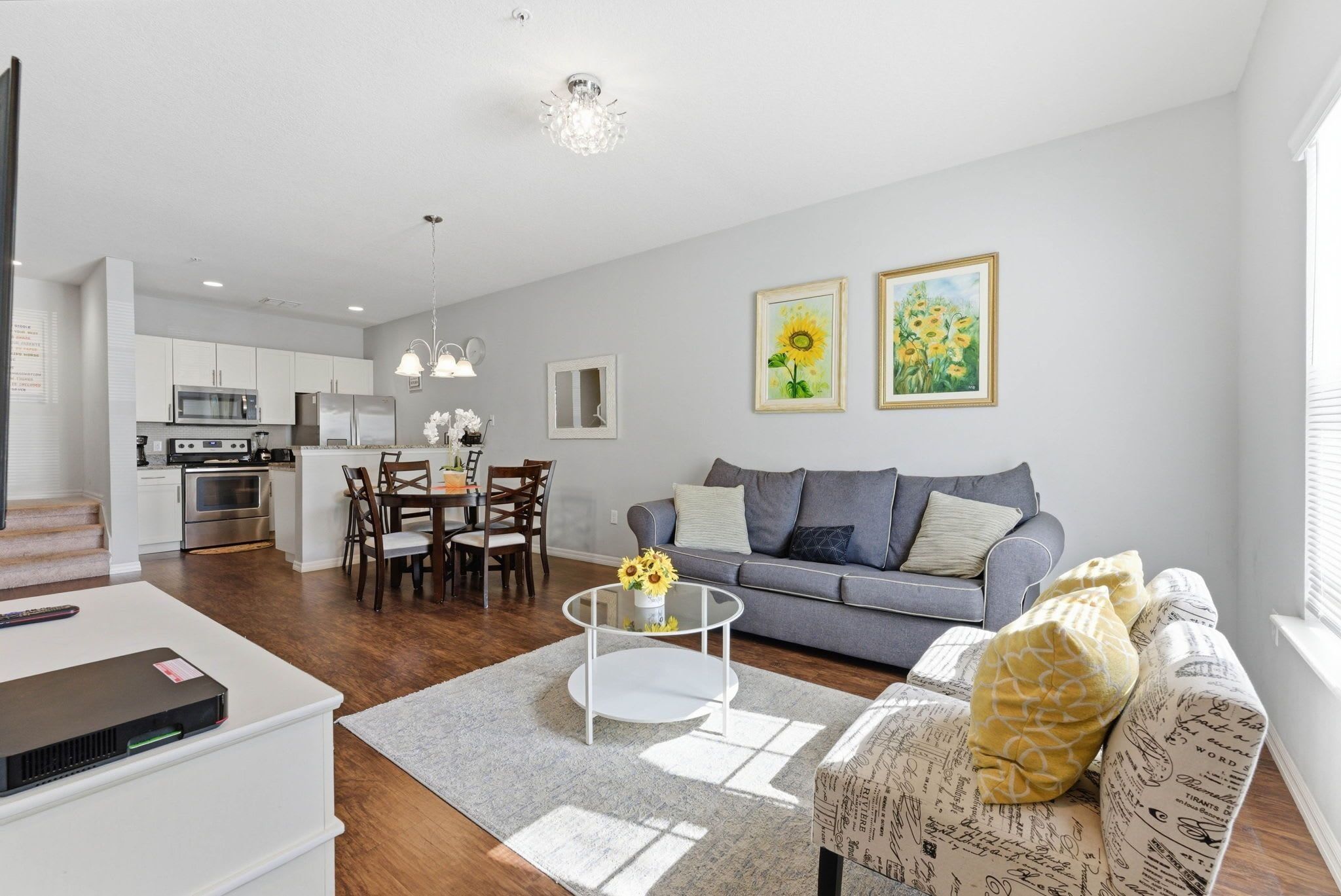 A modern living room with a grey sofa, a coffee table, and a dining area with a white table and chairs.