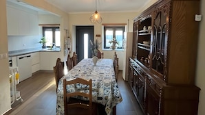 Uma cozinha ampla com área de refeições, destacando uma ilha central, armários de madeira e uma luminária pendente.