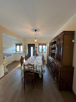 A spacious kitchen with a dining area, featuring a central island, wooden cabinets, and a pendant light. - Holiday Home 'Quinta De Fonte Coberta' with Mountain View, Wi-Fi and Air Conditioning (Lavradas)