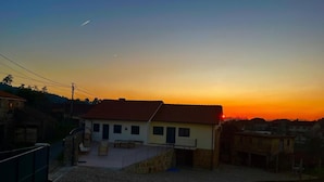 Zona residencial com uma casa, telhado com telhas, varanda e um pátio pavimentado.