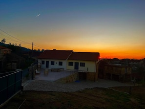 A residential area with a house featuring a tiled roof, a balcony, and a paved patio area. - Holiday Home 'Quinta De Fonte Coberta' with Mountain View, Wi-Fi and Air Conditioning (Lavradas)