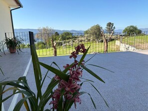 A balcony with a potted plant and a view of a fenced garden and distant mountains. - Holiday Home 'Quinta De Fonte Coberta' with Mountain View, Wi-Fi and Air Conditioning (Lavradas)