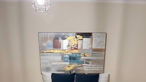 Quarto com cama, duas mesas de cabeceira, abajur e uma grande pintura abstrata na parede.
