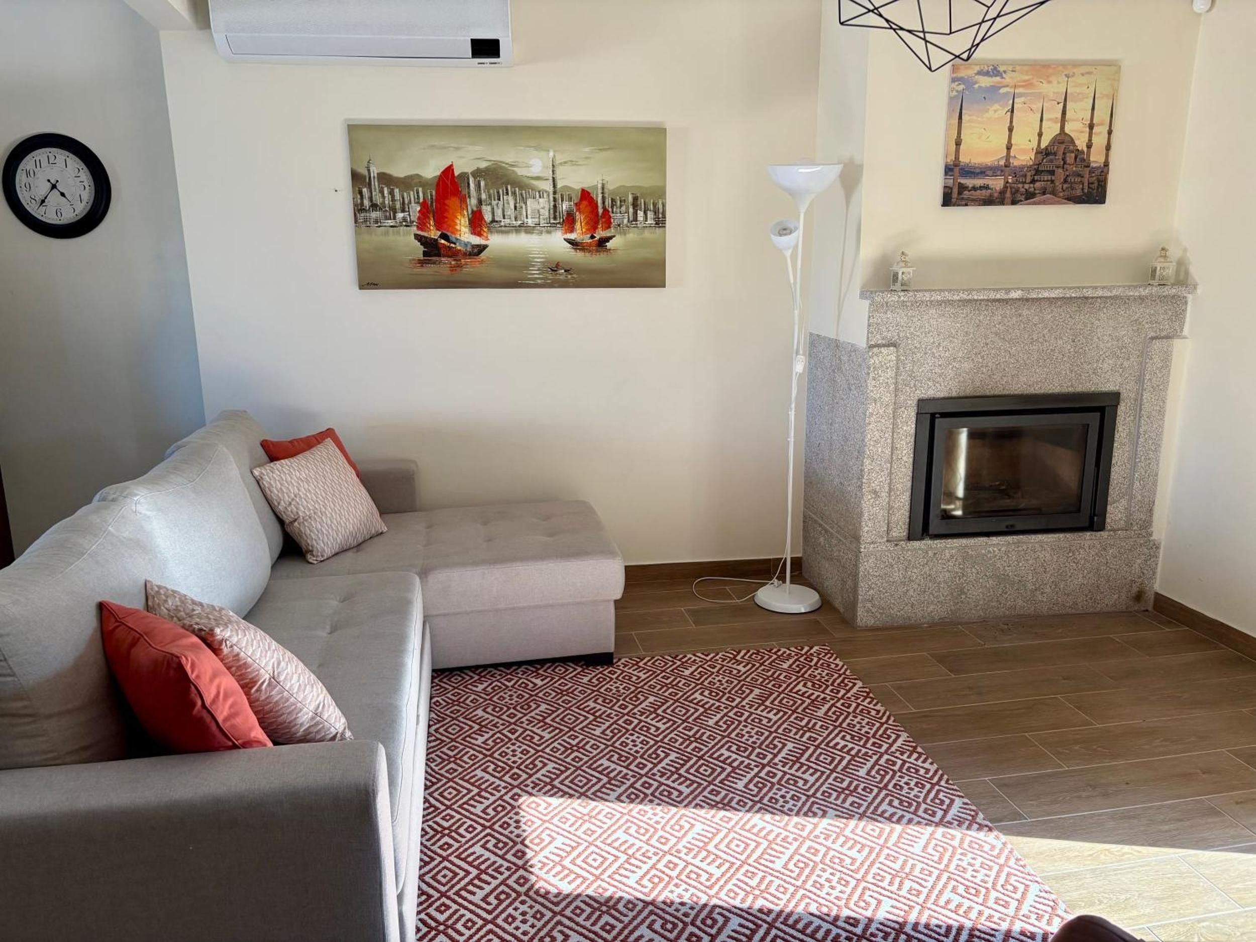 Un salon comprenant un canapé, un tapis à motifs, une cheminée et des œuvres d’art murales représentant un paysage urbain et une mosquée.