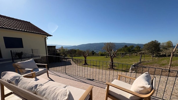Uma área de estar ao ar livre iluminada pelo sol, com vista para uma paisagem montanhosa.