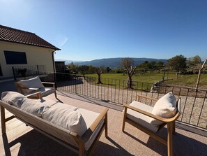 Un espacio exterior con mesas y sillas iluminado por el sol y vistas a un paisaje montañoso.