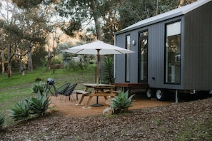A modern cabin with a patio area featuring a table, chairs, and an umbrella.