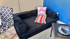 A black sofa with two pillows, one with a pink flamingo design and another with a red and white pattern. - Private Studio near Disney at Reunion Resort (Kissimmee)