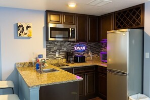 A compact kitchen with dark cabinetry, a stainless steel refrigerator, a microwave, and a coffee maker. - 2BR Condo Near Universal & I-Drive Attractions (Orlando)