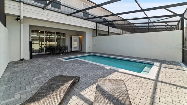 Una piscina exterior cubierta con zona de patio, que incluye una mesa y sillas.