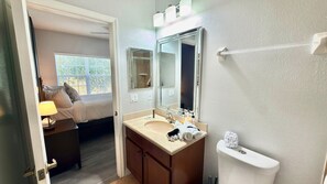 Un baño de hotel con lavamanos, espejo e inodoro.