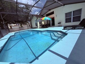 An outdoor swimming pool with a clear blue water surface, surrounded by a covered area with a roof structure. - Lake Berkley 3BR – Disney 10min, Pool & Lake (Kissimmee)