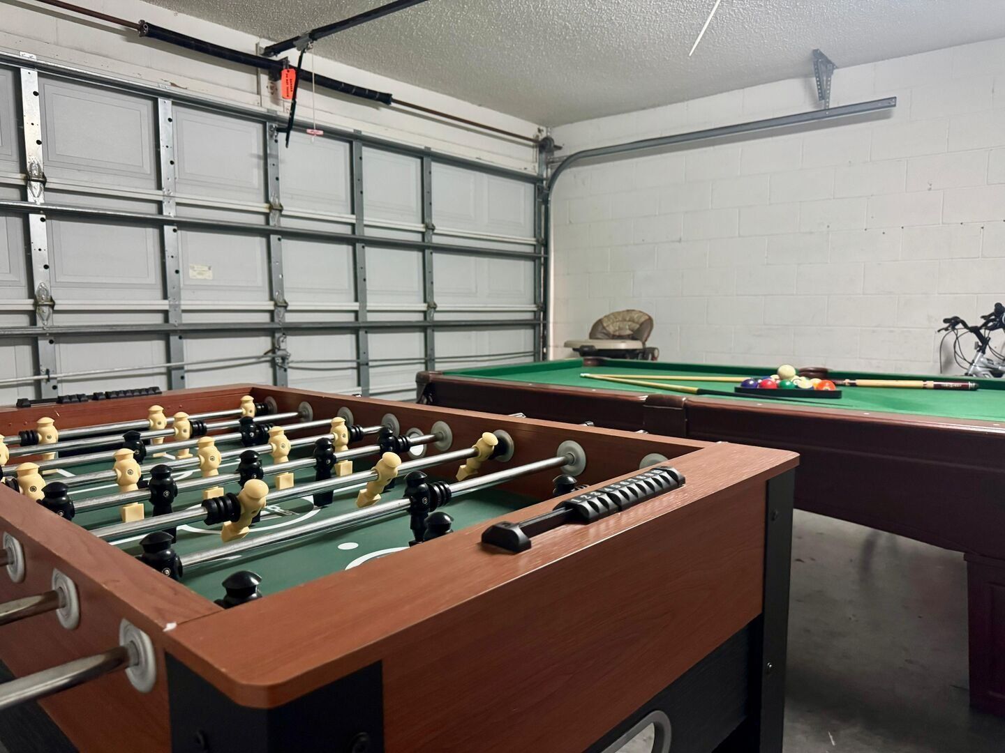 Una habitación con mesa de futbolín, mesa de billar y bicicleta.