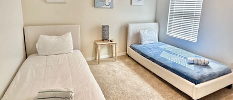 Un dormitorio con dos camas, una mesita pequeña y decoración en la pared.