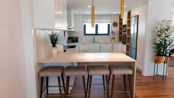 A modern kitchen with a central island, bar stools, a built-in oven, and pendant lighting.