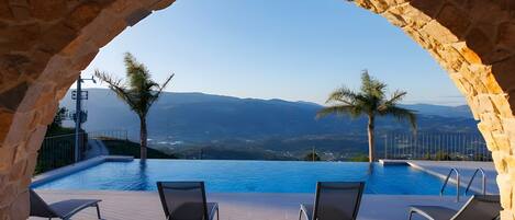 A pool area with two lounge chairs and a stone archway.