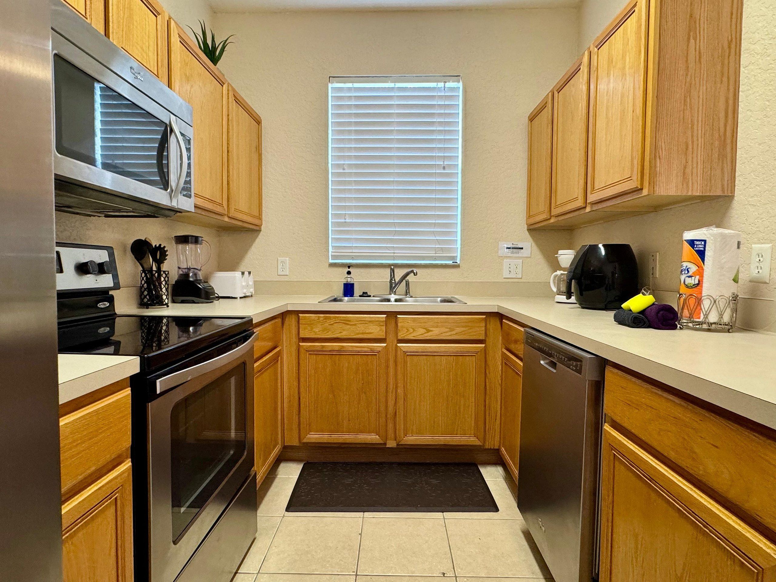 A kitchen with wooden cabinets, a microwave, a coffee maker, and a dishwasher.