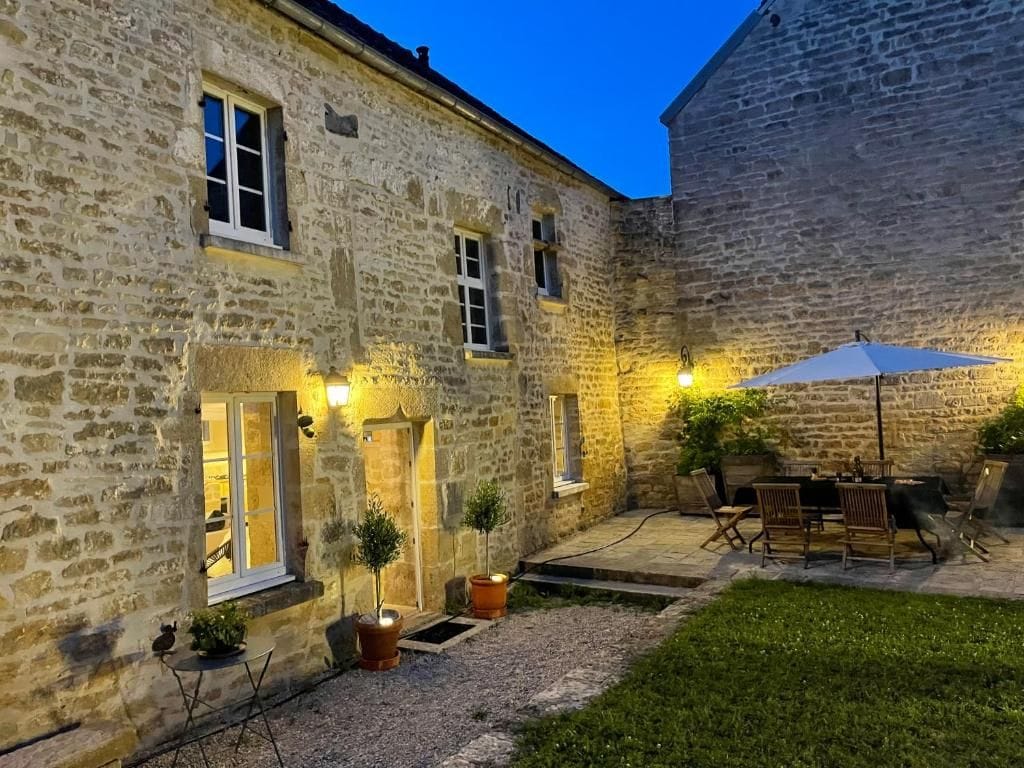 A stone building with a patio area, outdoor seating, and a small garden.