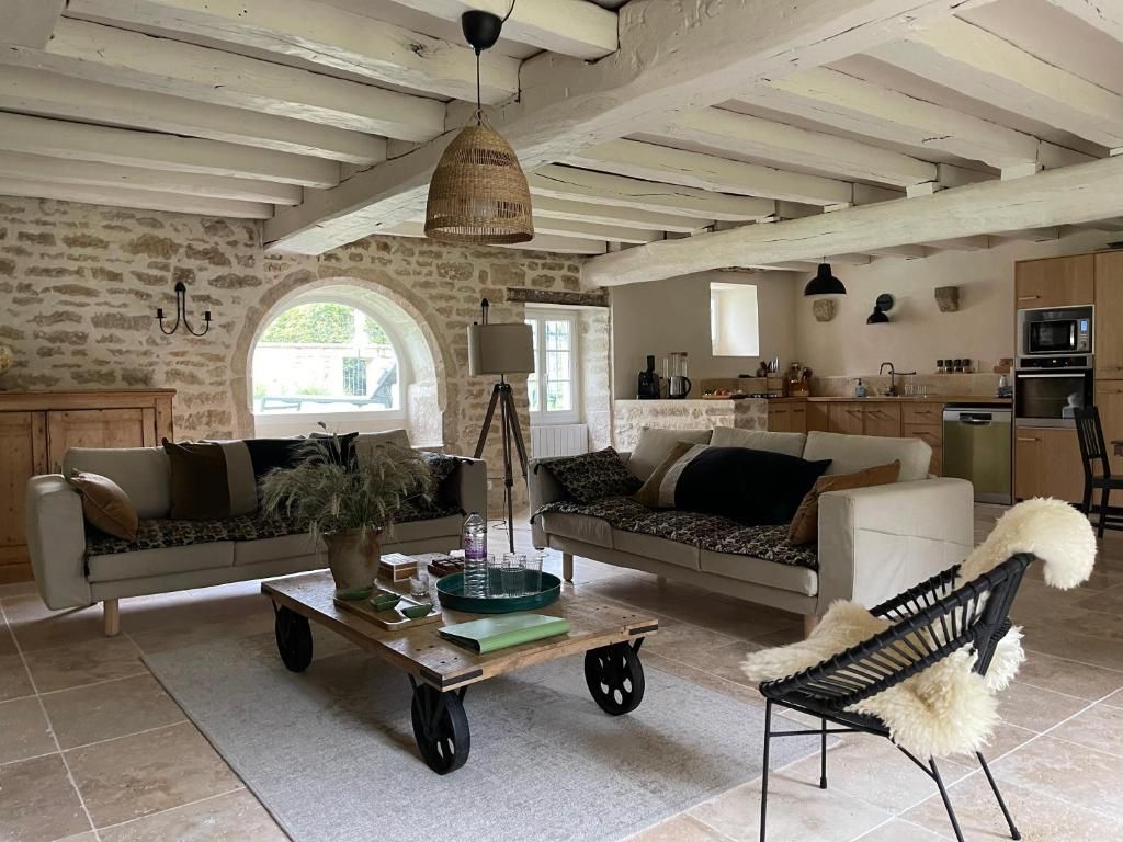 Ein rustikales Interieur mit Steinwänden, einer Holzbalkendecke, einem Essbereich mit Tisch und Stühlen sowie einer Küche mit modernen Geräten.