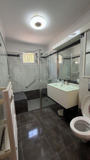 Une salle de bain moderne avec une douche à parois de verre, un lavabo blanc et des toilettes.