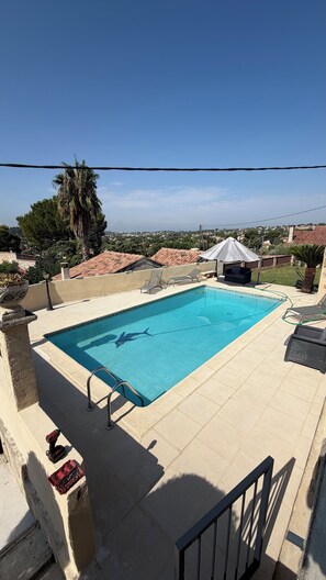Une piscine rectangulaire à l’eau d’un bleu limpide, entourée d’une terrasse carrelée.
