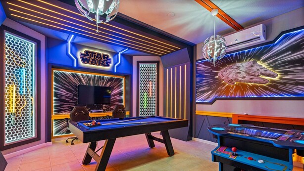 Una habitación con mesa de billar, una pared temática de Star Wars y una máquina de pinball.