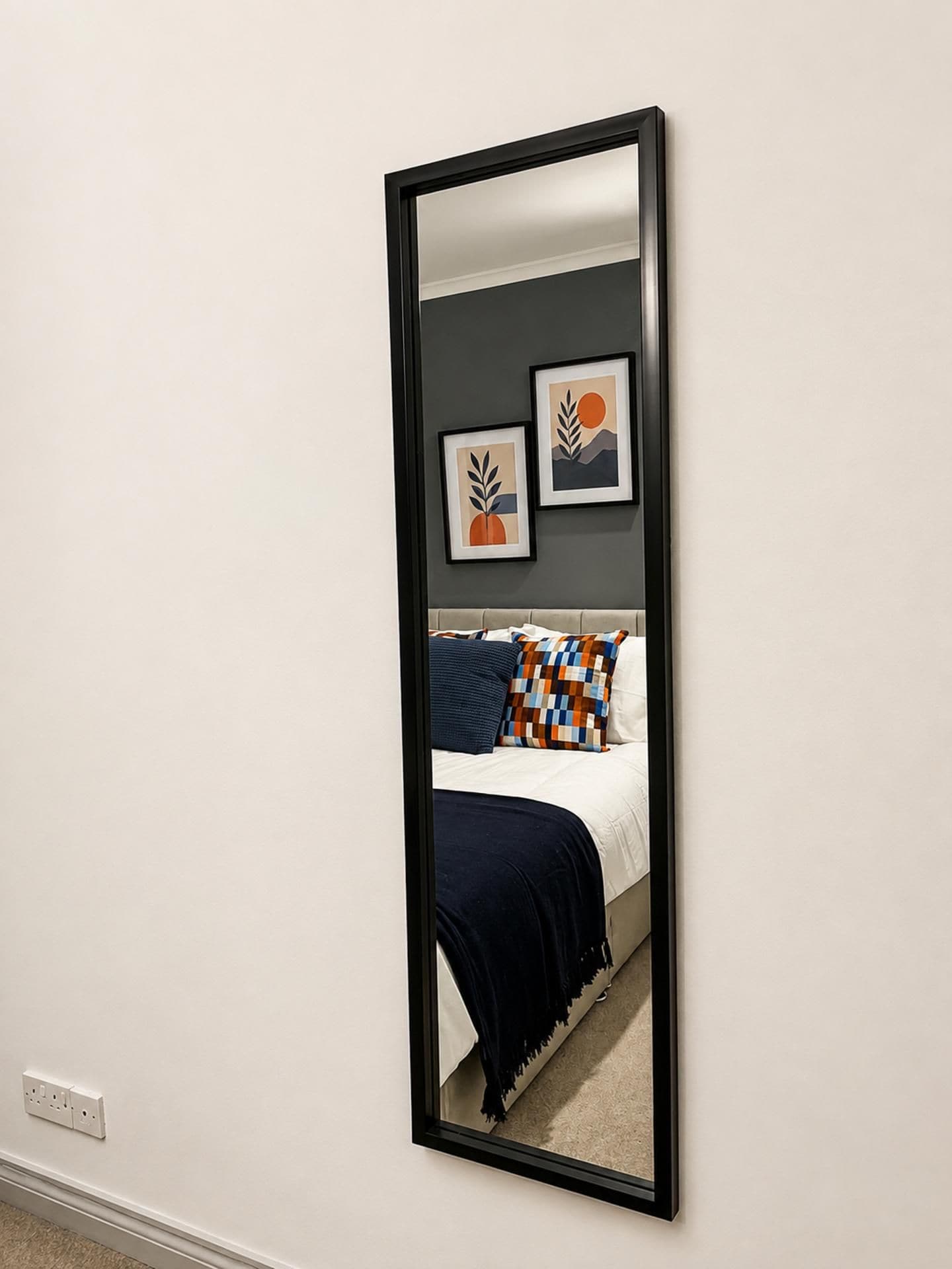 A mirror reflecting a bedroom with a bed, pillows, and artwork on the wall.