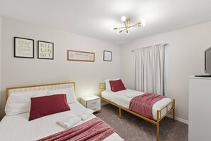Ett hotellrum med två separata sängar, ett nattduksbord med en lampa, en taklampa och tre inramade, inspirerande citat på väggen.