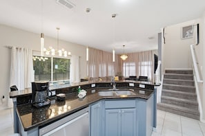 Een moderne keuken met een granieten aanrecht, een inbouwvaatwasser en een roestvrijstalen spoelbak.