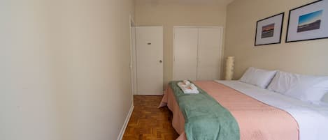 Une chambre d’hôtel avec un lit, une porte et deux tableaux encadrés au mur.