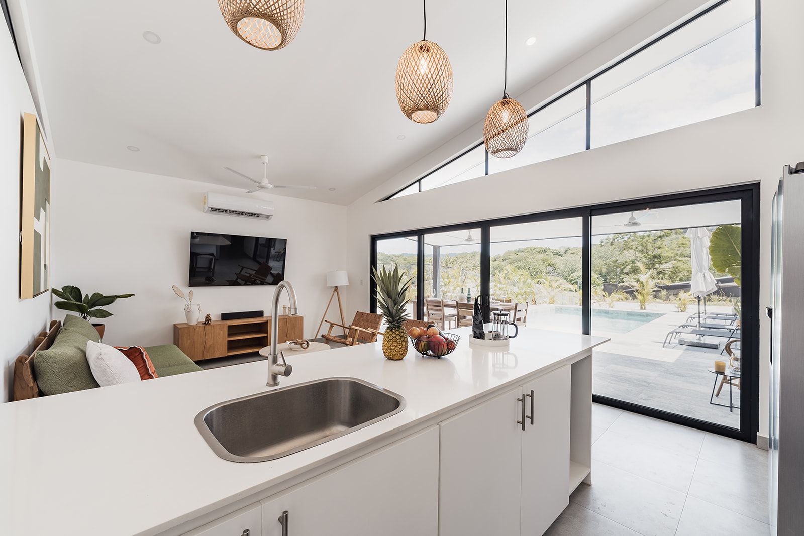 Una cocina moderna con una isla grande, un lavaplatos integrado y un comedor con vistas a una piscina.