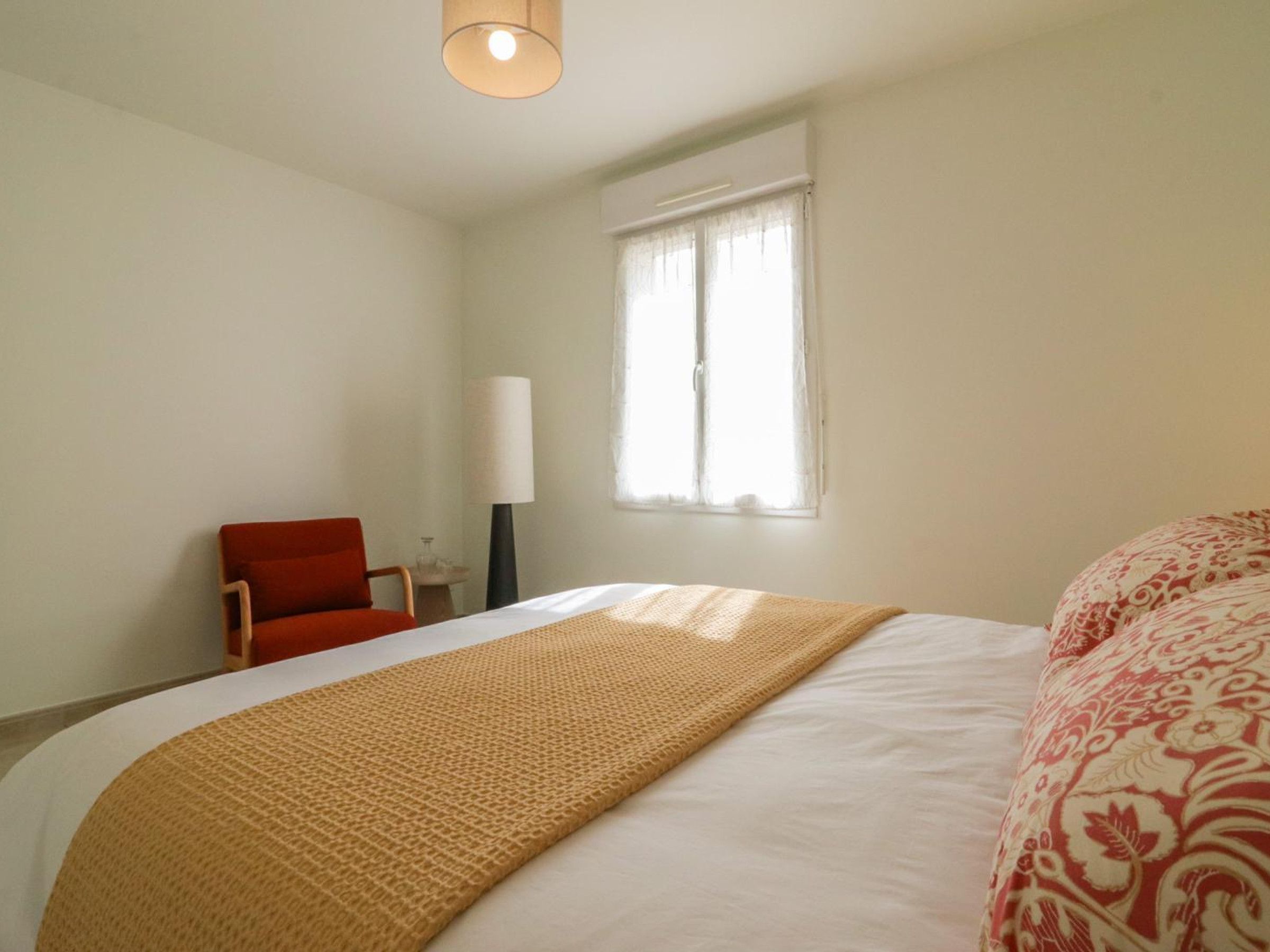 Een hotelkamer met een bed, een stoel, een lamp en een raam.