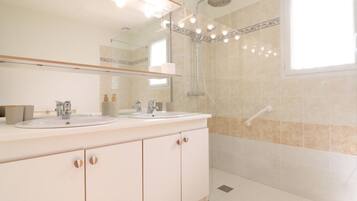 Een moderne badkamer met twee wasbakken, een douche en een grote spiegel.