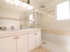 Un baño moderno con dos lavamanos, ducha y un espejo grande.