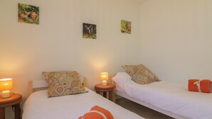 Quarto de hotel com duas camas, cada uma com travesseiro e uma pequena mesa de cabeceira com abajur.