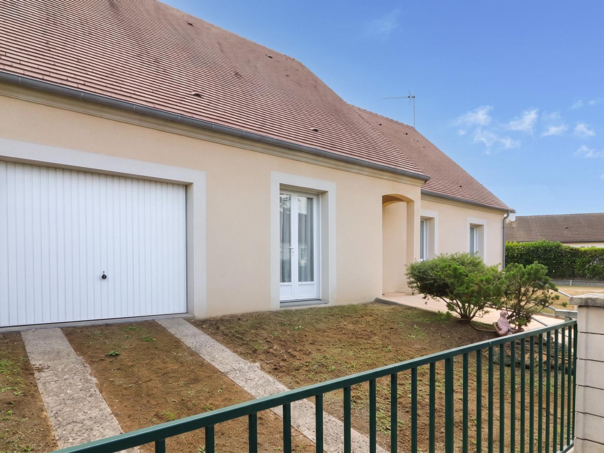 Een woonhuis met garage, overdekte veranda en een kleine tuin.