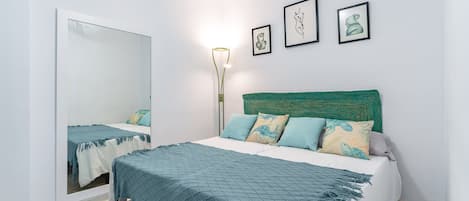 Quarto com cama, espelho e três obras de arte emolduradas na parede.